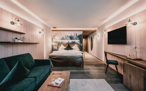 Baumtraum Modern hotel room with woodland-themed wall art, velvet sofa, and wooden furnishings